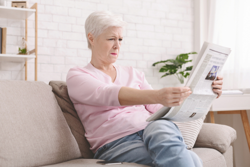 woman holding newspaper far away to read